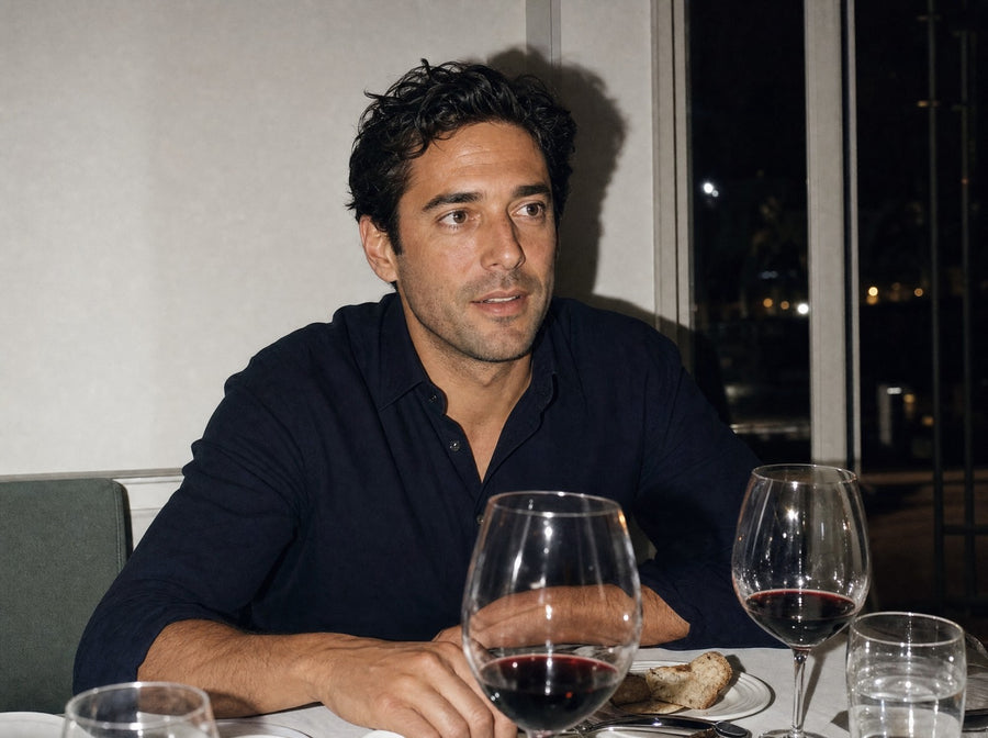 A man at a dinner table with glasses of red wine
