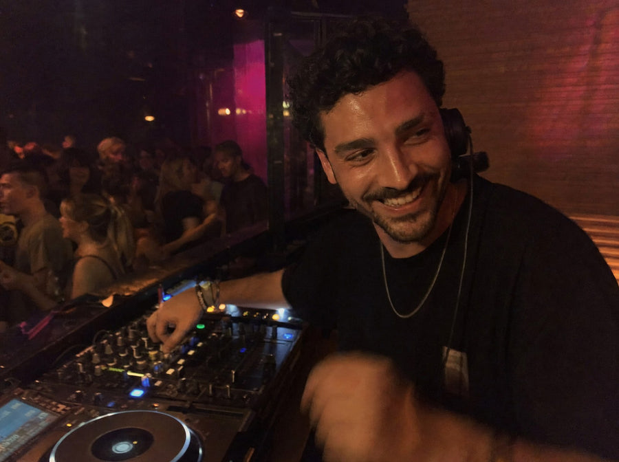 A DJ smiling behind the decks at a club