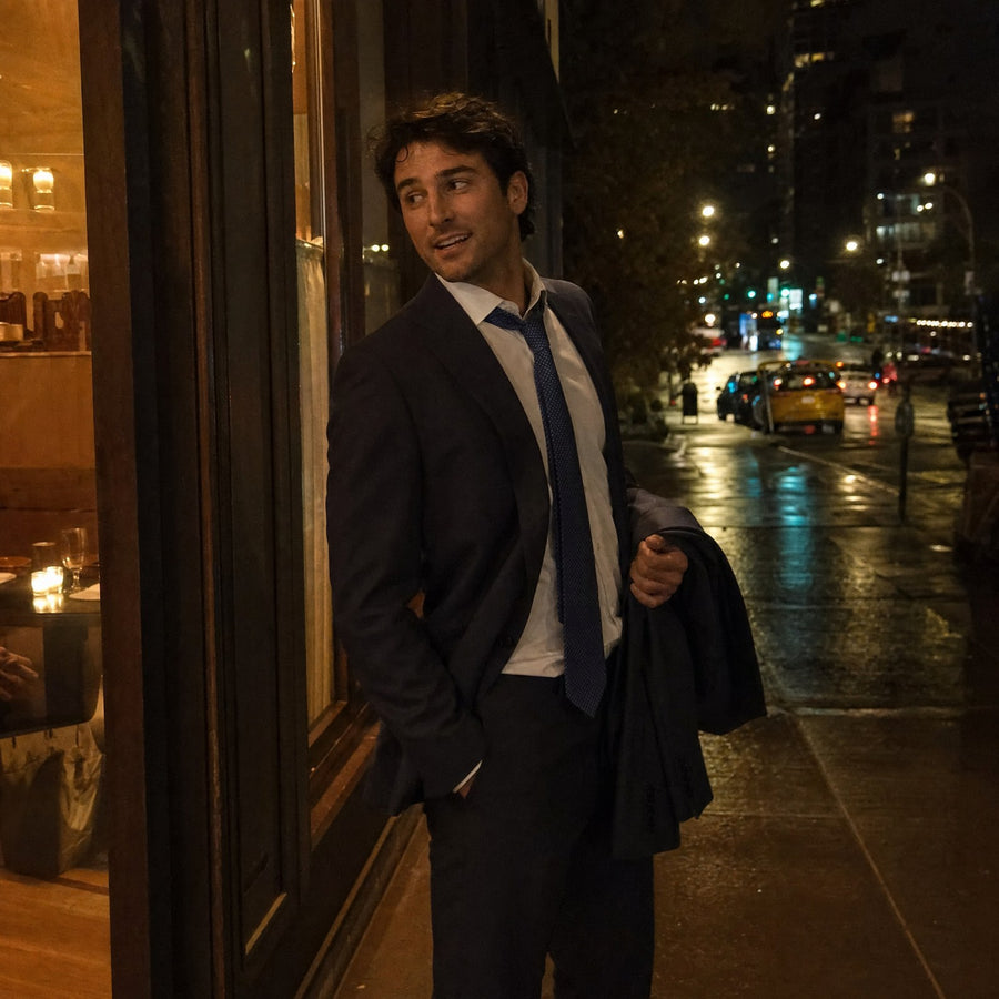 A man in a suit leaving a restaurant on a city street at night